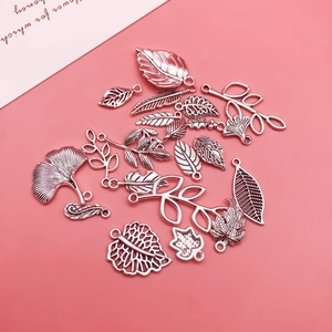 Detailed macro view of silver alloy leaf and feather pendants for DIY jewelry making