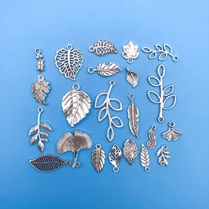 Flat lay of vintage silver leaf and feather alloy charms for DIY jewelry making