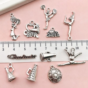 Macro detail of antique silver cheerleader charms with scale ruler on pink surface