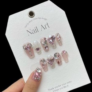 Kit de faux ongles roses avec cœurs en cristal 3D, papillons argentés et perles sur fond noir