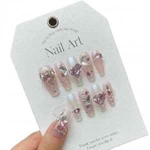 Faux ongles roses et blancs avec strass en forme de cœur et détails de perles