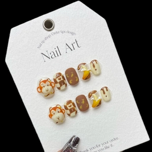 Handmade press-on nails featuring 3D cartoon monkey and banana designs in brown and cream