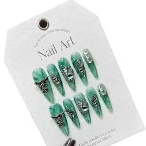 Green marble stiletto press-on nails with silver gothic wings and eye charms