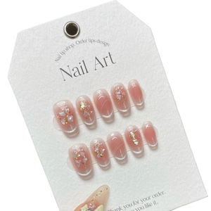 Pink cat-eye press-on nails with gold foil, shell shards and pearl accents on white card