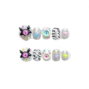 Y2K style press-on nails with cartoon evil eye and heart charms on a white background