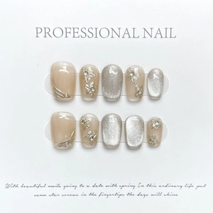 Cat eye press-on nails with 3D metallic flowers and rhinestone details on nude base