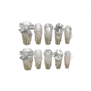 Faux ongles faits main avec paillettes argentées, strass et nœuds métalliques élégants
