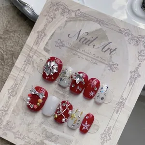 Handmade Christmas press-on nails with red snowflakes, pearls, and rhinestones