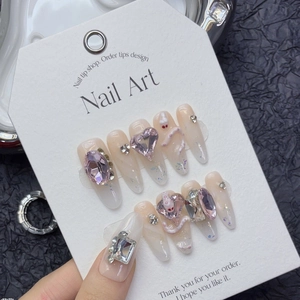 Faux ongles roses avec strass en cœur et accents argentés sur carte de présentation