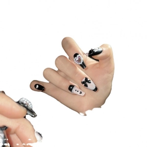 Handmade press-on nails with black bows and pearl heart gems on white background