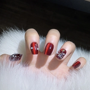 Handgefertigte rote Cat-Eye-Nägel mit Weihnachtsstern- und Perlendekorationen