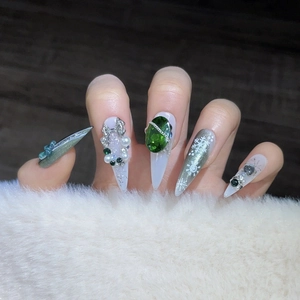 Christmas stiletto press-on nails with green gems, silver bows and snowflake cat eye art