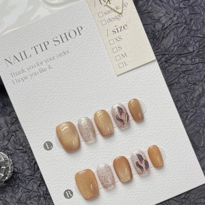 Handmade golden cat-eye press-on nails set with purple gemstones on a black textured background