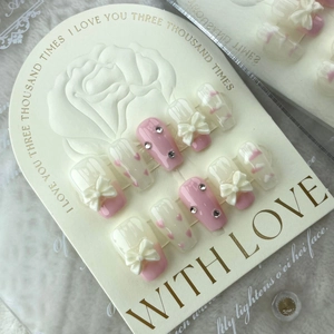 Pink press-on nails with 3D cream bows, rhinestones, and hand-painted hearts on display card