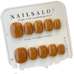 Glossy caramel amber press-on nails in short oval shape on professional display card