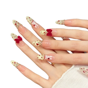 Press-on nails featuring red velvet bows, gold glitter gradient, and rabbit nail art
