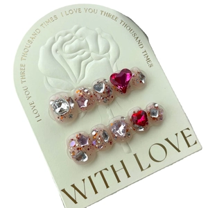 Sparkling pink heart press-on nails with glitter and rhinestones on white card