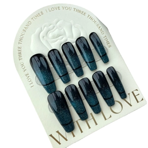 Handmade emerald cat eye press-on nails with blue-black gradient and silver glitter on display