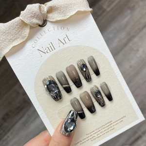 Uñas postizas hechas a mano con degradado gris-negro y pedrería oscura en pantalla