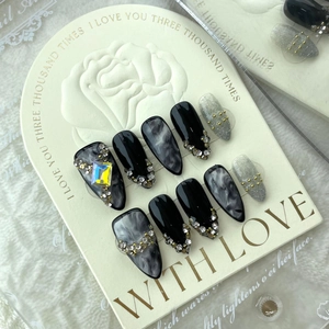 Handmade almond press-on nails with dark marble ink design and silver glitter finish