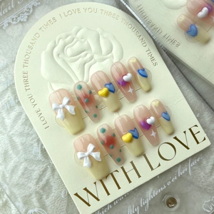 Handmade press-on nails with cream heart patterns and 3D bows in pastel candy colors