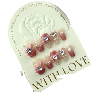 Pink gradient handmade press-on nails with 3D bows, rhinestones, and pearls on display