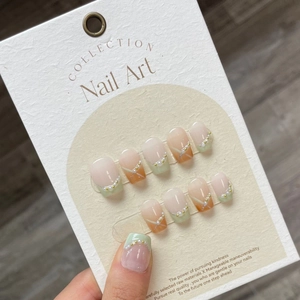 Handmade press-on nails featuring nude gradient, green French tips, and pearl accents