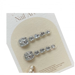 Silver rhinestone nail art charms with crystal accents on textured paper display