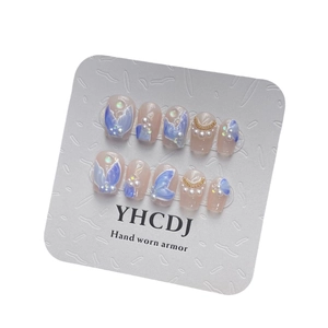 Handmade mermaid style press-on nails with 3D pearls, shell flakes, and wing art on a display card