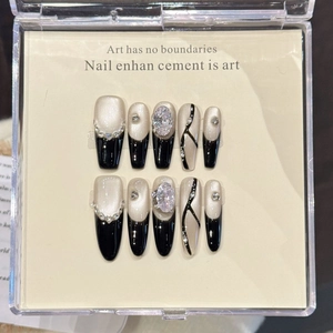 Handmade short press-on nails in ivory and black with gems in a display box