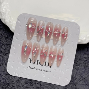Handmade stiletto press-on nails with pink gradient, rhinestones and pearls on display