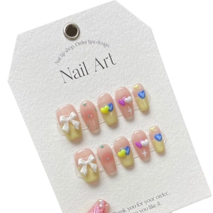 Handmade press-on nails with macaron heart patterns and 3D bow tie nail art