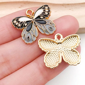 Macro detail of enamel butterfly charm showing front textures and polished gold alloy back