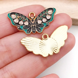 Detailed macro view of black enamel butterfly pendant with white lily of the valley floral pattern