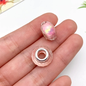 Makroaufnahme von zwei facettierten rosa irisierenden Harzperlen mit Silberkern für DIY-Schmuck