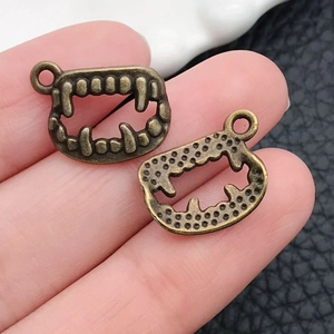 Close-up of vintage bronze tusk pendants held by hand for DIY jewelry making