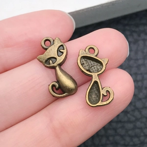 Macro shot of bronze cat charms showing detailed front and back textures for DIY jewelry