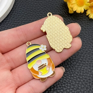 Macro-opname van een kabouter-bijen-hanger met emaille voorkant en gouden metalen rug