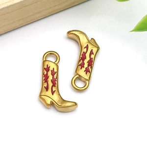Detail of gold cowboy boot pendants with red enamel flame patterns and jump rings