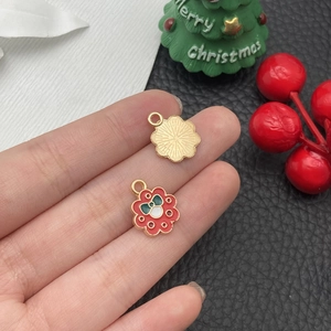 Detail eines roten Emaille-Weihnachtsblumenanhängers für DIY-Schmuck in der Hand