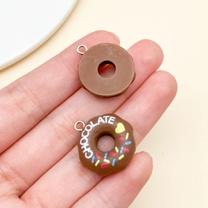 Macro shot of 3D chocolate donut resin charms with gold metal rings for DIY crafts