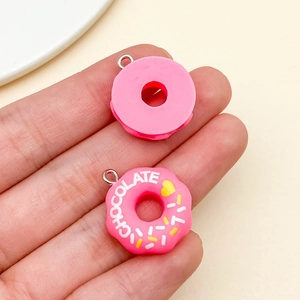 Detailed view of pink resin donut charms with chocolate text and silver metal rings
