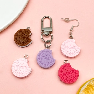 Colorful resin biscuit keychains and jewelry pendants on a soft pink background