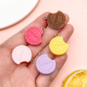 Hand holding colorful resin biscuit pendants in chocolate pink and purple colors