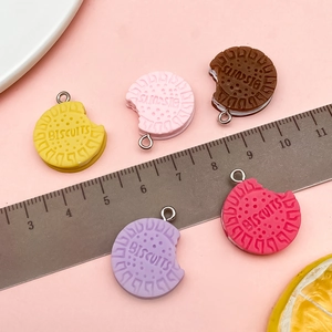 Close-up of five colorful resin biscuit charms with realistic bite marks and metal loops