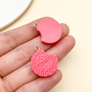 Macro detail of pink resin biscuit charm with realistic bite mark and metal ring