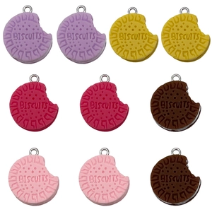Colorful resin biscuit charms set with bite marks and metal rings on white background