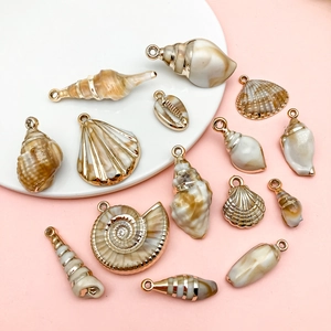 Flat lay of laser-plated acrylic ocean sea shells and conch charms for DIY jewelry making
