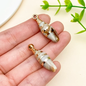 Detail of acrylic laser-plated sea shell charms with gold stripes held in hand