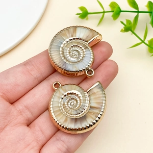 Detail of nautilus shell pendants with gold plating held to show size and texture